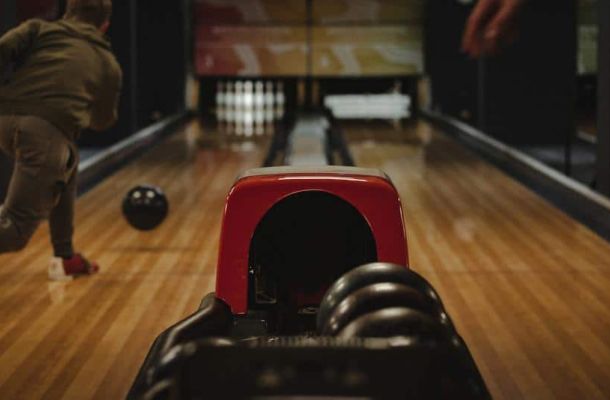 bowling balls, player throwing ball down the lane at pins, indoors