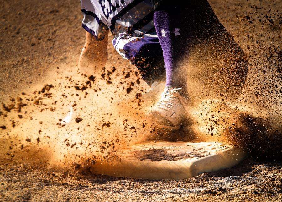 softball sliding into base with dirt flying outdoors